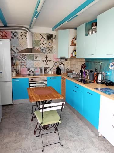 a kitchen with blue cabinets and a wooden table at Apartman Barby Jadranovo in Jadranovo