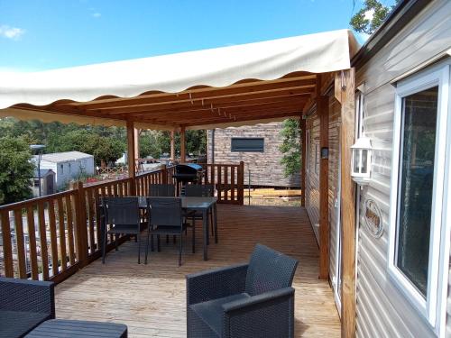 une terrasse en bois avec des chaises, une table et un auvent dans l'établissement résidence de vacances soleiluna, à Rocbaron
