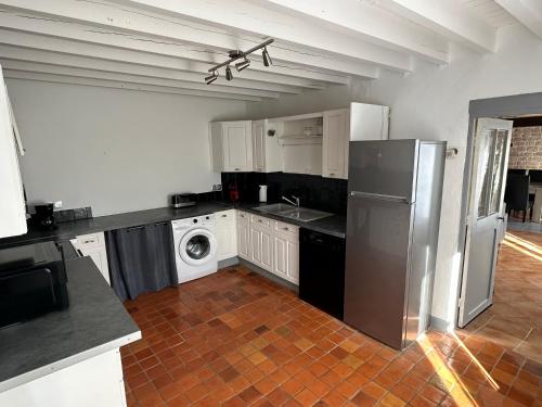 une cuisine avec un réfrigérateur et une machine à laver dans l'établissement Entre pierres & mer, à Fresville