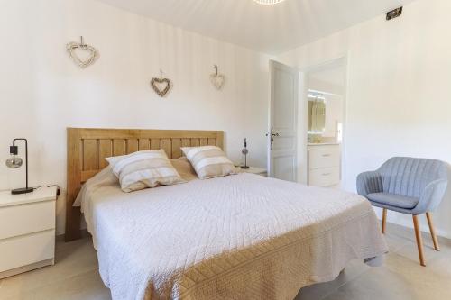 - une chambre blanche avec un lit et une chaise bleue dans l'établissement Le Petit Nid, à Saint-Rémy-de-Provence