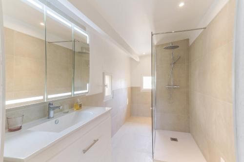 une salle de bain blanche avec un lavabo et une douche dans l'établissement Le Petit Nid, à Saint-Rémy-de-Provence
