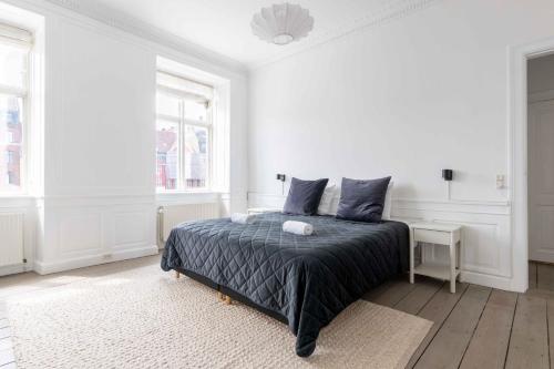 a white bedroom with a bed and two windows at Chic Apartment in Vibrant Area by Copenhagen Canals in Copenhagen