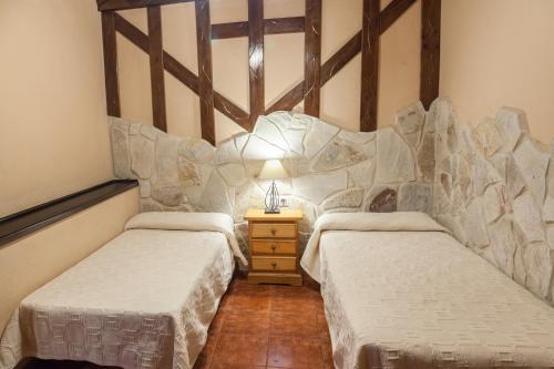 a room with two beds and a table with a lamp at Complejo Turístico Las Cañadas Casas de Campo- Actividades Gratuitas Todos los Fines de Semana in Baños de Montemayor