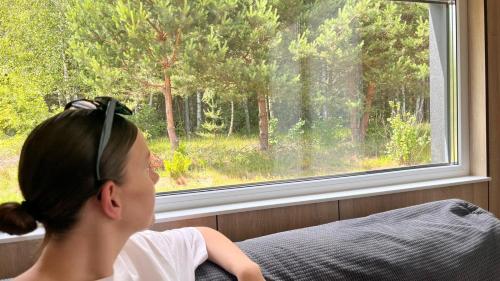 a young girl sitting on a couch looking out a window at Arche Siedlisko Miedwieżyki in Milejczyce