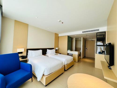 a hotel room with a bed and a blue chair at The KH Cam Ranh Nha Trang Beachside in Thôn Hòa Ða
