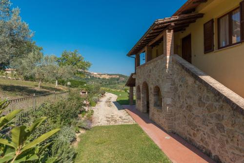a stone house with a pathway next to a building at The Grapevine by MANVI in Montepulciano