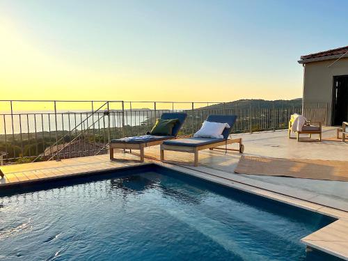 - une piscine avec deux chaises assises sur une terrasse dans l'établissement Villa San Joseph, à Cargèse
