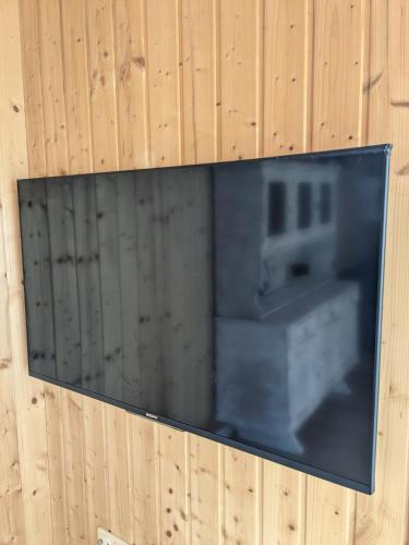 a television hanging on a wooden wall at Ruhiges Ferienhaus mit Sauna: Hellaberg III in Langenbach