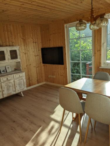 a dining room with a table and chairs and a television at Ruhiges Ferienhaus mit Sauna: Hellaberg III in Langenbach