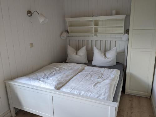 a bed with white sheets and pillows in a room at Ruhiges Ferienhaus mit Sauna: Hellaberg III in Langenbach