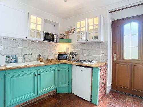 une cuisine avec des placards verts et un comptoir dans l'établissement Charmante maison, à Joux-la-Ville