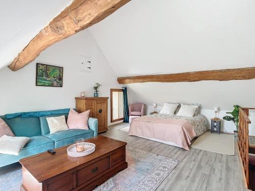ein Wohnzimmer mit einer blauen Couch und einem Bett in der Unterkunft Charmante maison in Joux-la-Ville
