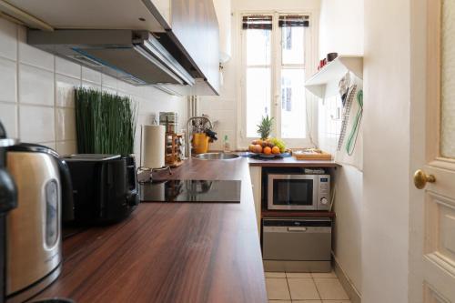 kuchnia z blatem ze zlewem i kuchenką mikrofalową w obiekcie Le Marais cosy-comfy appartment w Paryżu