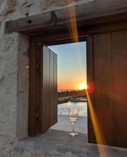 a glass of wine in a window with the sunset at Terra Lucis Mountain Residences in Agios Leon