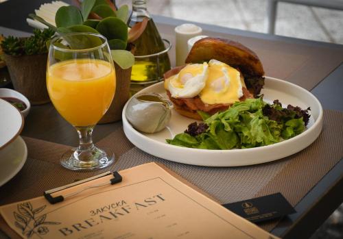 プロブディフにあるATLAS HOUSE Luxury Suitesの食べ物の皿とオレンジジュースのグラスが置かれたテーブル