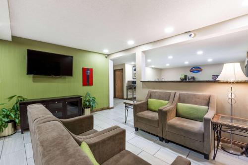 a living room with couches and a flat screen tv at Baymont by Wyndham Louisville South I 65 in Brooks