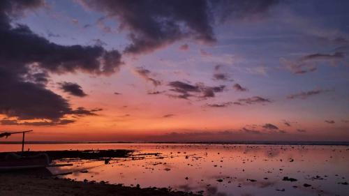 a sunset over a body of water with clouds at Uncle Hippie's Dream in Gili Meno