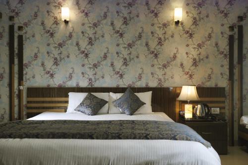 a bedroom with a large bed with a floral wallpaper at Hote Meghnath Palace in Dhupguri