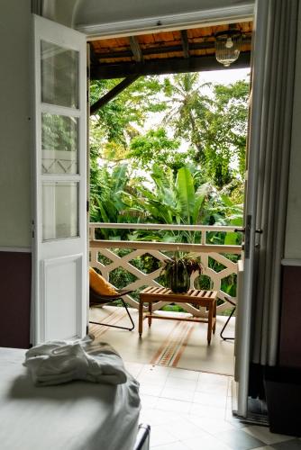 a room with a door open to a balcony with a table at Roça Sundy - Principe Collection in Santo António