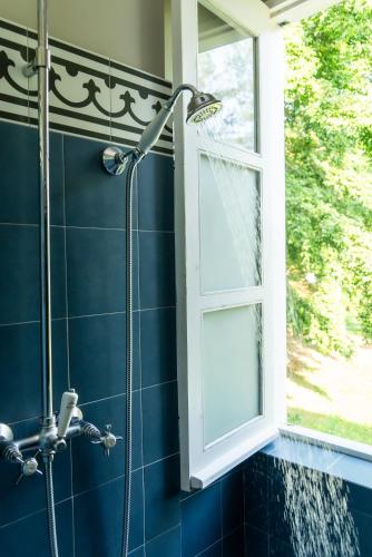 a shower in a blue bathroom with a window at Roça Sundy - Principe Collection in Santo António