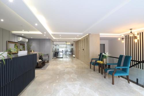 a lobby with blue chairs and a table at Ahuja Residency Mayfield Garden in Gurgaon