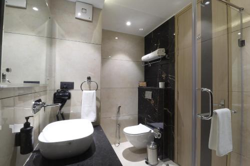 a bathroom with a toilet and a glass shower at Ahuja Residency Mayfield Garden in Gurgaon