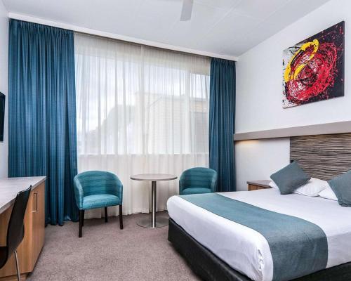 a hotel room with a bed and a table and chairs at Comfort Inn Regal Park in Adelaide