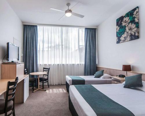 a hotel room with two beds and a table at Comfort Inn Regal Park in Adelaide