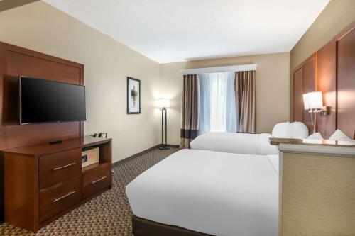 a hotel room with a bed and a flat screen tv at Comfort Suites - Jefferson City in Jefferson City