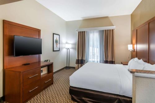 a hotel room with a bed and a flat screen tv at Comfort Suites - Jefferson City in Jefferson City