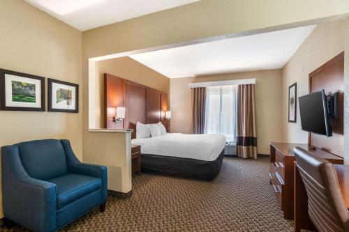 a hotel room with a bed and a blue chair at Comfort Suites - Jefferson City in Jefferson City