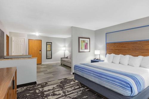 a hotel room with a bed and a living room at AmericInn by Wyndham Pella in Pella