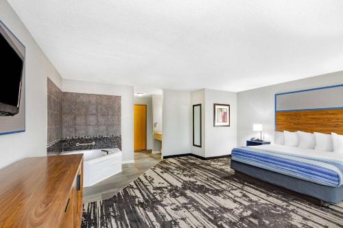 a hotel room with a bed and a tub at AmericInn by Wyndham Pella in Pella