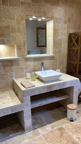 La salle de bains en pierre est pourvue d'un lavabo et d'un miroir. dans l'établissement Chalet en Drôme Provençale, à Roussas