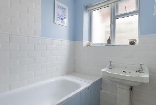 une salle de bain blanche avec une baignoire et un lavabo dans l'établissement Forest Cottage, à Lymington