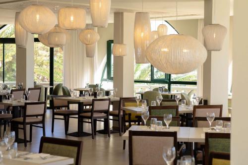 a restaurant with tables and chairs and chandeliers at Hilton Mallorca Galatzo in Paguera