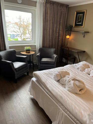 a bedroom with a bed and two chairs and a window at Smedjebackens Pensionat in Smedjebacken