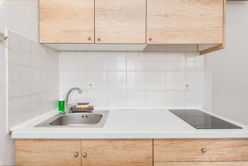 a kitchen with a sink and a white tiled wall at Katerina's Garden Mola Kaliva in Mola Kalyva