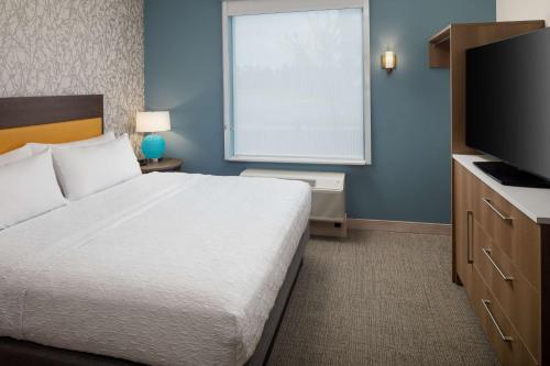 a bedroom with a large bed and a large window at Home2 Suites By Hilton Wilmington Medical Park Downtown in Wilmington
