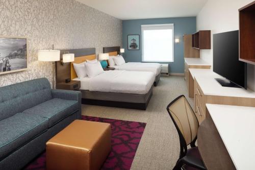 a hotel room with a bed and a couch at Home2 Suites By Hilton Wilmington Medical Park Downtown in Wilmington