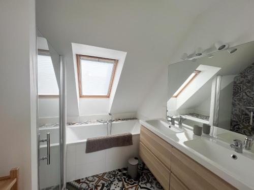 un bagno bianco con lavandino e specchio di La maison des dunes - Proche plage Sainte Marguerite a Landéda
