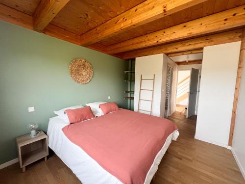 una camera da letto con un letto grande in una stanza con soffitti in legno di La maison des dunes - Proche plage Sainte Marguerite a Landéda