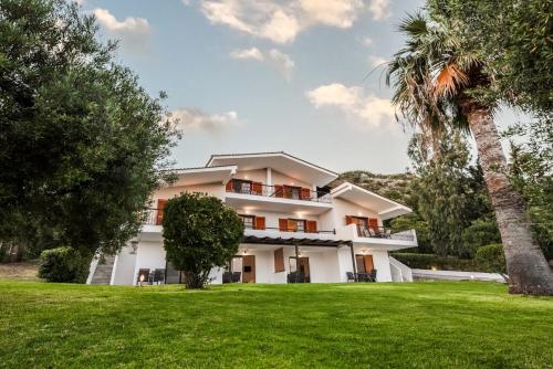 a large white house with a palm tree at Katerina's Garden Mola Kaliva in Mola Kalyva