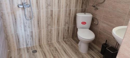 a bathroom with a white toilet and a shower at Стаи за гости Пансионът на Роуз Вълшебната ми Кръстница in Chernomorets