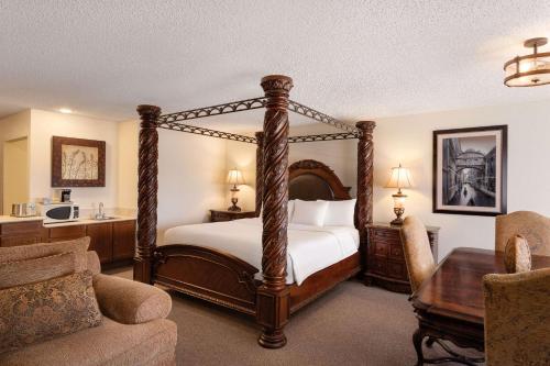 a bedroom with a four poster bed and a desk at Radisson Hotel Colorado Springs Airport in Colorado Springs
