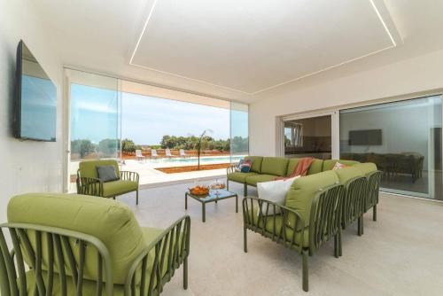 a living room with green furniture and a large window at Villa Donnosanto a 5 minuti dalla spiaggia, Ostuni 10 minuti in Torre Santa Sabina