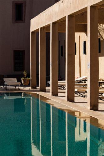 a pool of water with columns and a building at Kanz Erremal in Merzouga