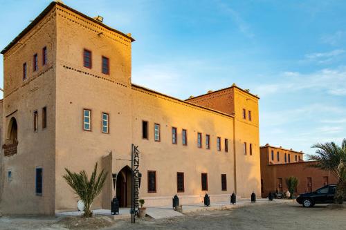 a large brick building with the sun shining on it at Kanz Erremal in Merzouga