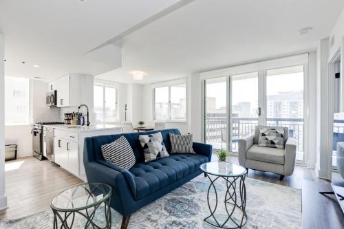a living room with a blue couch and a kitchen at Capitol Convenience 2BR Luxury Minutes from DC in Arlington