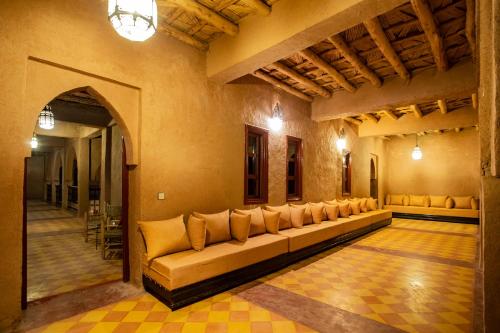 a living room with a long couch in a room at Kanz Erremal in Merzouga